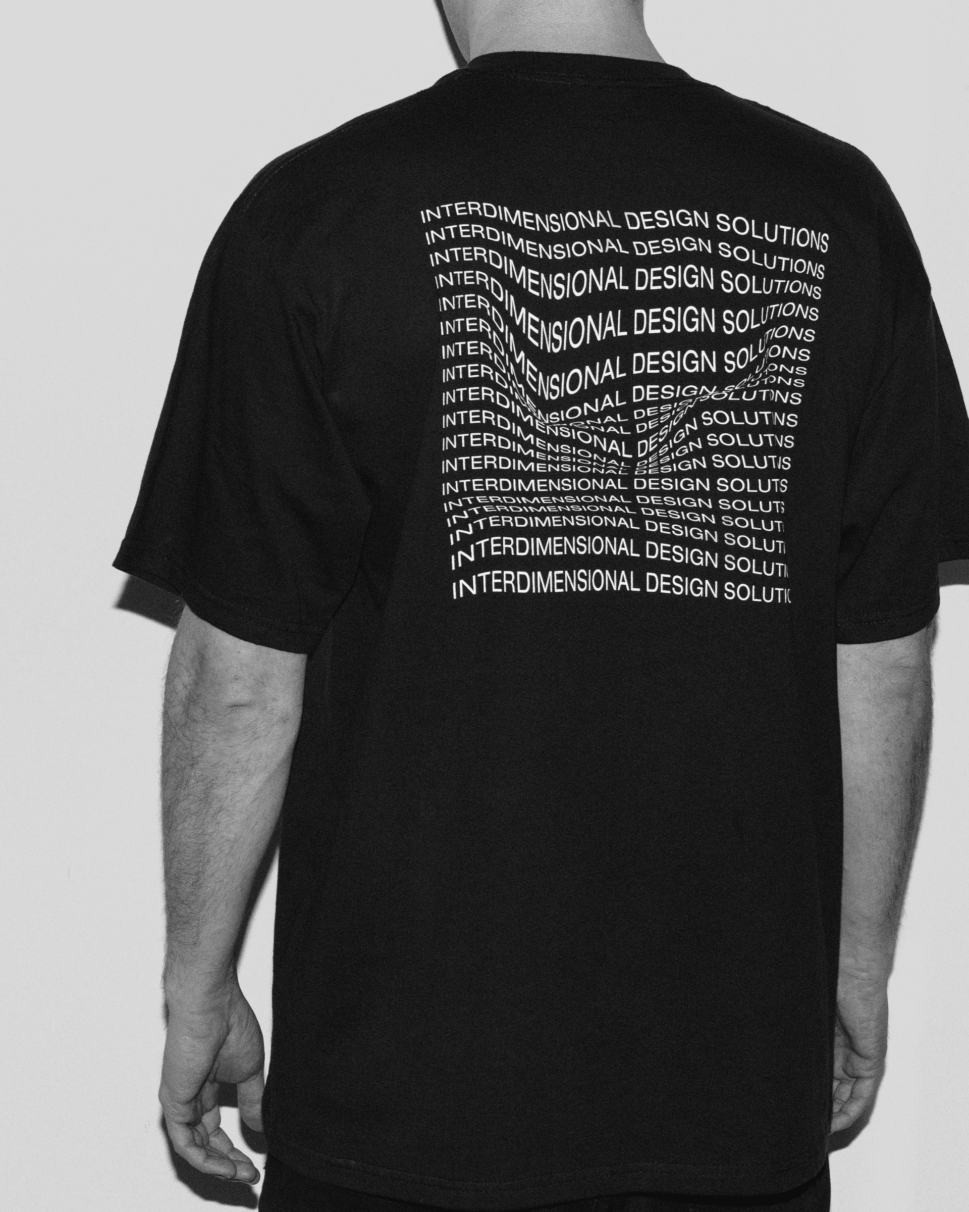 Back view of the black tshirt worn by a man with big 'Interdimensional Design Solutions' print