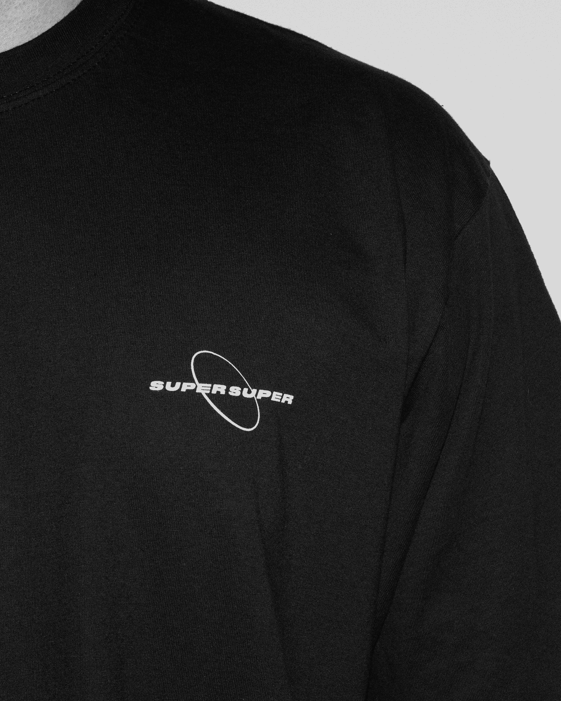 Zbliżenie na klatkę piersiową czarnego tshirtu z białym logiem Super Super na piersi